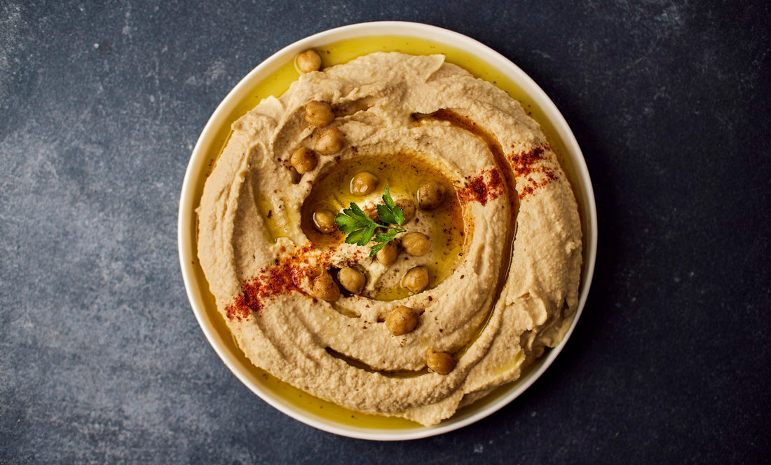 Bowl of creamy hummus with olive oil and garnish